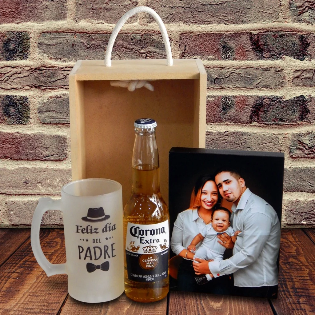 Una caja de regalo del Día del Padre que incluye una jarra de cerveza con el texto "Feliz Día del Padre", una botella de cerveza Corona Extra y una foto de una familia sonriente.
